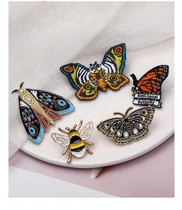 Set of 5 enamel butterfly and honeybee pins with colorful drip oil finish on ceramic plate
