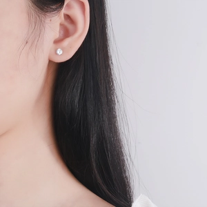 Sparkling four-prong zircon stud earrings with silver metal base worn by a model