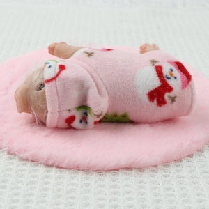Close-up of a mini silicone piglet doll wearing a pink snowman patterned onesie outfit
