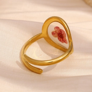 Gros plan sur la bague en acier doré 18K avec détail de fleurs séchées rouges