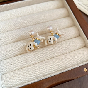 Macro detail of cute puppy earring with pearl and blue zircon in a wooden jewelry box