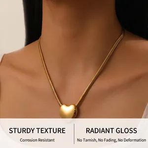 Dettaglio di una collana con ciondolo a cuore dorato e catena a serpente su modella
