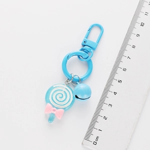 Detail view of a blue lollipop keychain with bell and bow showing exact dimensions