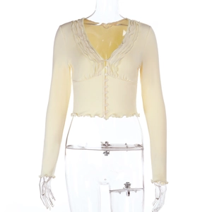 Detail of light yellow slim fit cropped cardigan with ruffled trim and deep V-neckline