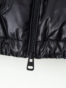 Detail of the high-gloss black puffer jacket showing a resin zipper and elastic hem