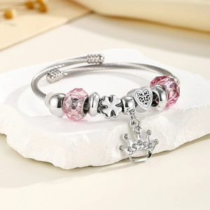 Macro detail of stainless steel crown charm and pink crystal beads on adjustable bracelet
