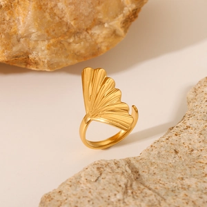 Gold ginkgo leaf open ring in stainless steel displayed on a natural textured stone