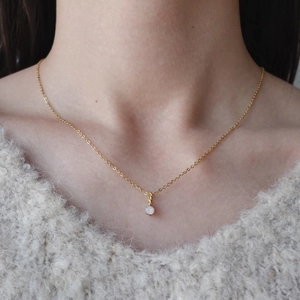Collana in acciaio al titanio dorato con ciondolo in opale bianco tondo su modella