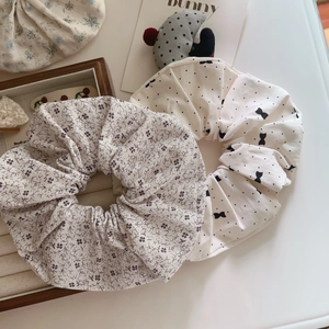 Detail of floral and bow pattern cotton scrunchies set on minimalist wooden display
