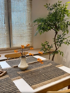 Close-up of hand-woven paper and jute placemat with natural fringe and striped texture
