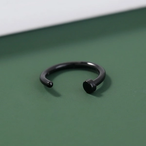 Macro view of black coated U-shaped nose ring with flat disc end and smooth finish