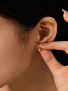 Close-up of model wearing small gold 14K stainless steel four-point star stud earrings
