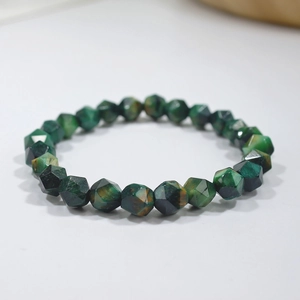 Macro shot of faceted green tiger eye stone beads on a minimalist beaded bracelet