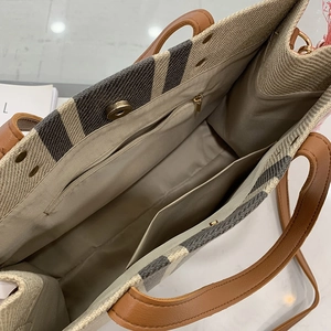 Large striped canvas tote bag with brown leather handles and spacious interior compartments