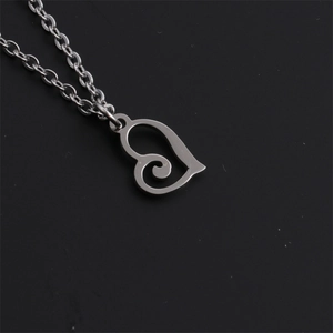 Macro detail of a silver heart pendant with spiral design on a titanium steel necklace