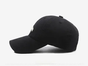 Side view of black cotton baseball cap showing curved brim and white embroidery detail