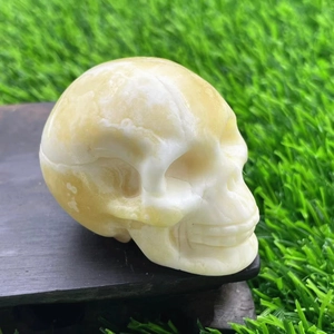 Close-up of a 7cm hand-carved crystal skull on a wood base over green grass