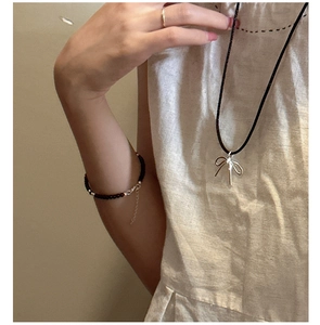 Detail of s925 silver bow pendant necklace with adjustable black cord on a model