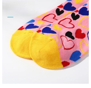 Détail de chaussette en coton rose à cœurs colorés et pointe jaune sans couture