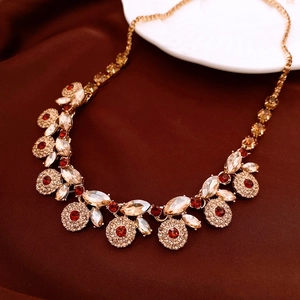 Detail of vintage style gold necklace with red crystals on dark red satin background