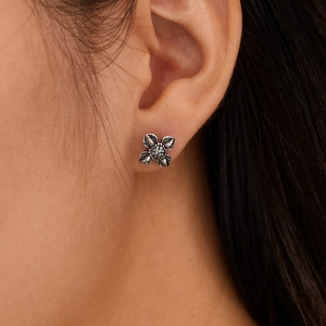 Men's titanium steel floral stud earring with retro silver finish shown on ear