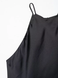 Detailed close-up of glossy black satin fabric with slim shoulder straps on a dress