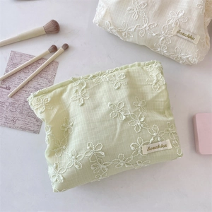 Detail of floral lace embroidery on cream and light green portable cosmetic bags