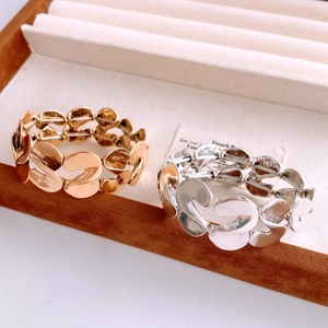 Detailed close-up of S-shaped matte gold and silver elastic bracelets in a jewelry box