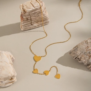 Minimalist gold heart necklace with four pendants styled on stones for elegant gift