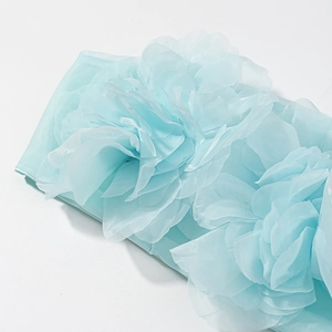 Détail du haut en mousseline bleu clair avec pétales de fleurs 3D et texture mesh douce