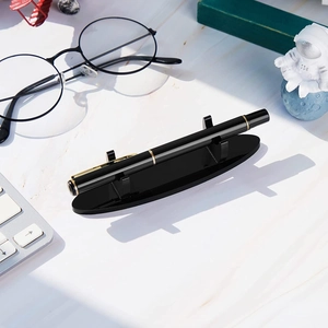 Minimalist black acrylic pen display stand on a marble desk with office accessories