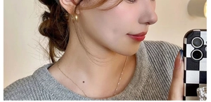 Close-up of minimalist golden hoop earrings and thin necklace set worn by a model