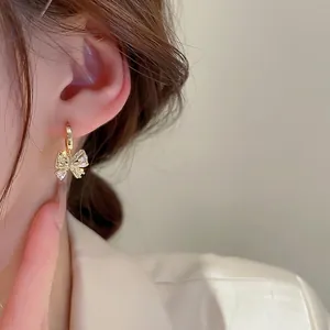 Gold plated bowknot earrings with sparkling zircons shown on a female model