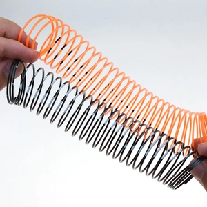 Close-up of orange and black plastic spring toy being stretched by hands for decompression