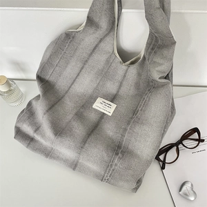 Detail shot of tie-dye grey canvas tote bag with textured fabric on a white desk