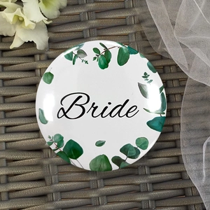 Detail of Bride badge with green leaf wreath on white background for wedding parties