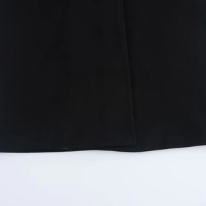 Detailed macro view of the black coat hemline featuring precise vertical stitching