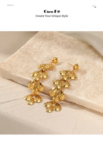 Detail of long gold drop earrings with textured sunburst metal discs on stone