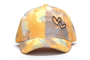 Close-up of children's baseball cap with rhinestone heart details in yellow pattern.
