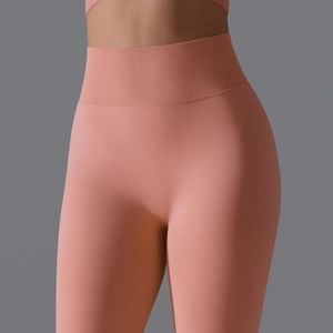 Detail of high-waist ribbed waistband and seamless breathable fabric on peach yoga leggings