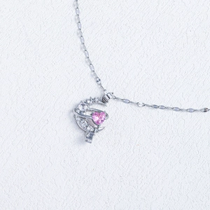 Macro shot of silver moon pendant featuring a pink heart gem and diamond accents