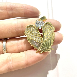 Detail of gold angel wing pendant with heart-shaped stone and micro-pave zircons