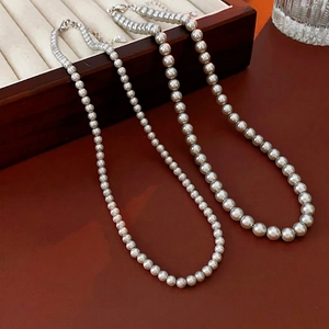 Elegant vintage pearl necklace set with gradient and uniform beads on a wood box