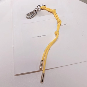 Gros plan du porte-clés en corde tressée jaune vif avec fermoir métallique sur magazine