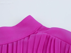 Dettaglio della spalla plissettata e del collo alto sull'abito in chiffon rosa