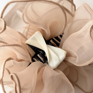 Détail des couches de maille d'organza champagne sur une grande pince à cheveux florale