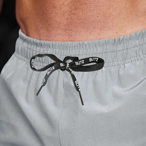 Close-up of elastic waistband on grey sports shorts with adjustable branded drawstrings
