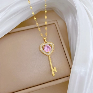Macro shot of gold heart-shaped key pendant with pink gemstone and zircons