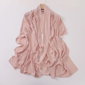 Detail view of the soft pink crepe hijab fabric draped elegantly on a wooden hanger