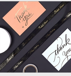 Macro detail of black satin ribbon with gold Happy Birthday foil print for gift wrapping